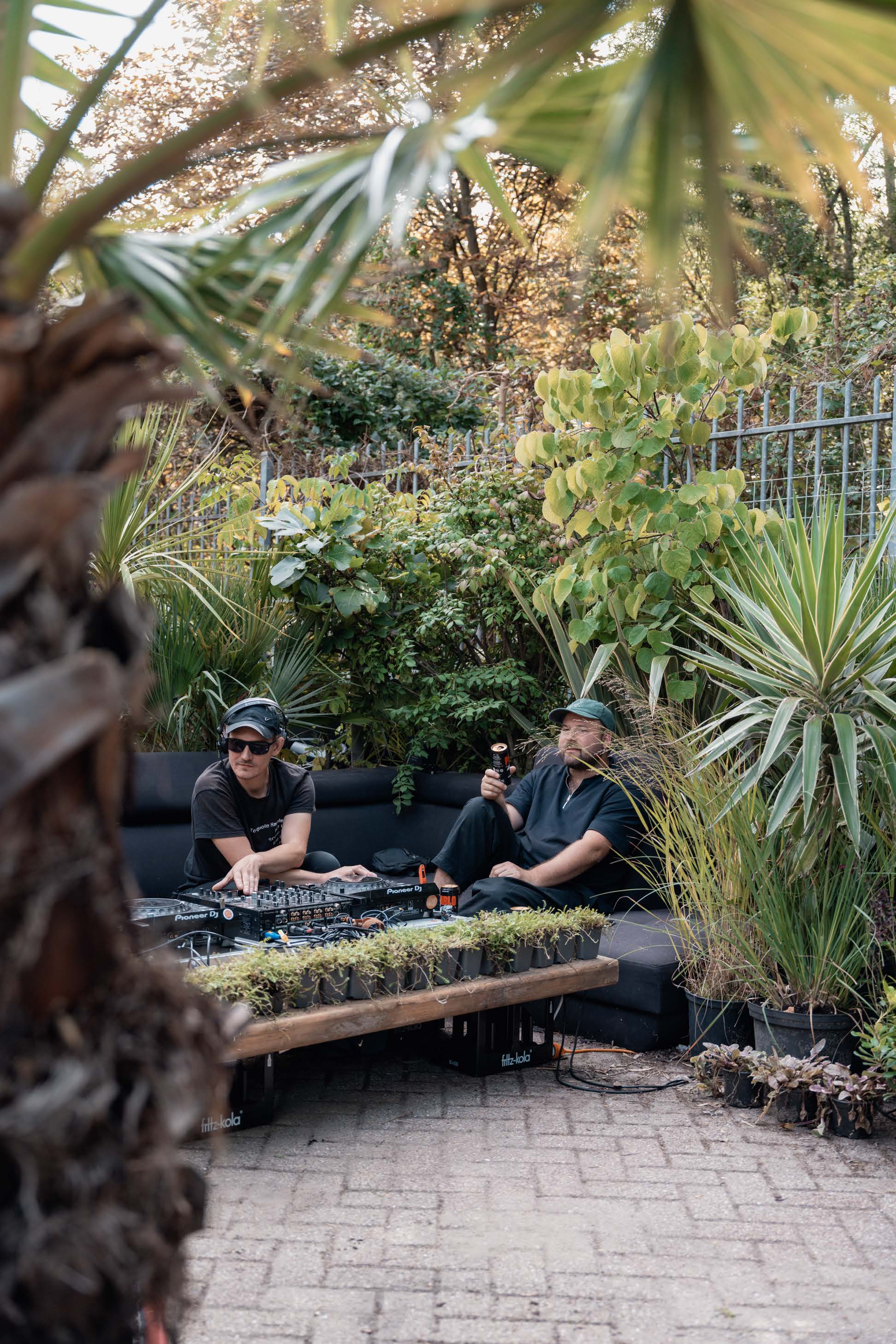 Two DJs playing a garden set beside cans of Pablo Beer.
